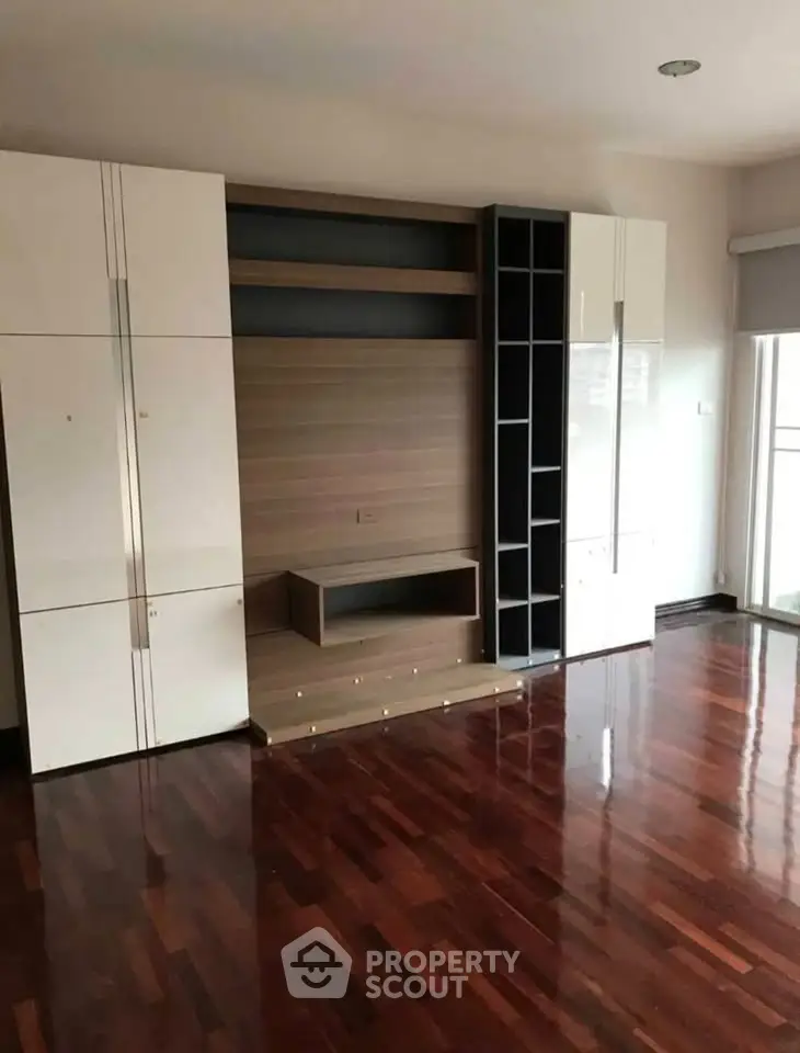 Spacious living room with elegant wooden flooring and modern built-in storage units.