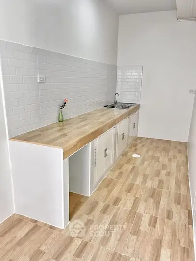 Modern minimalist kitchen with wooden countertops and white tile backsplash