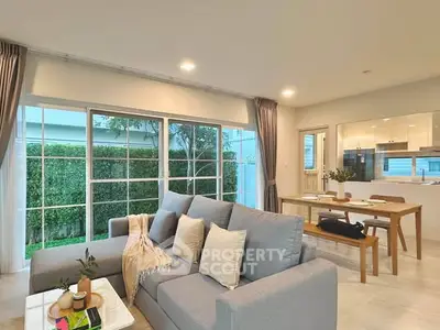 Spacious living room with modern decor and garden view, featuring a cozy sofa and dining area.
