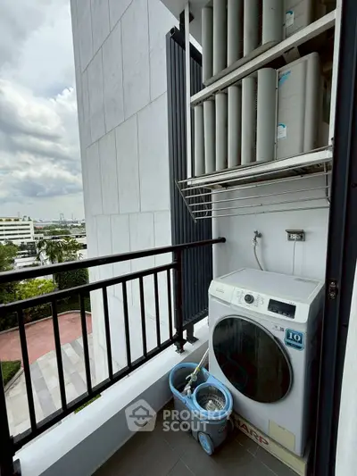 Compact balcony with washing machine and city view, ideal for urban living.