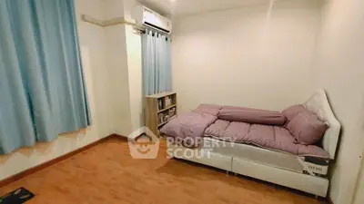 Cozy bedroom with wooden flooring and air conditioning, featuring a comfortable bed and ample natural light.