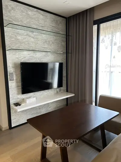 Modern living room with wall-mounted TV and glass shelves, featuring a cozy seating area.