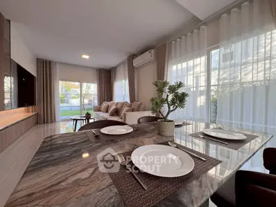 Elegant open-plan living and dining area with modern decor and large windows