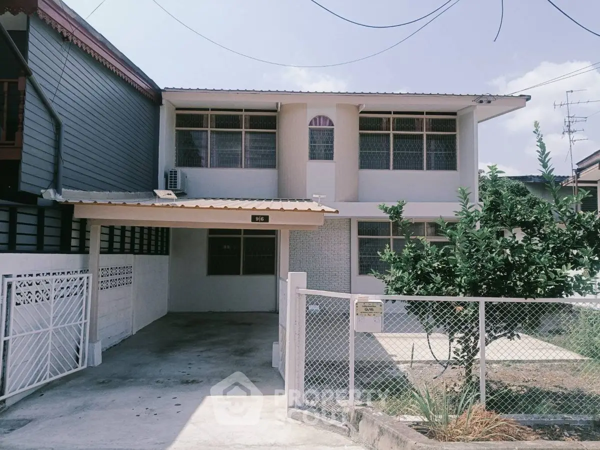 Charming two-story house with gated driveway and lush garden in a serene neighborhood.