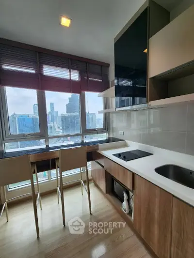 Modern kitchen with city view, featuring sleek cabinetry and breakfast bar seating.