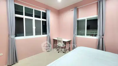 Cozy bedroom with pink walls, large windows, and a study desk.