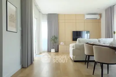 Modern living room with elegant decor, featuring a cozy sofa, wall-mounted TV, and stylish dining area.