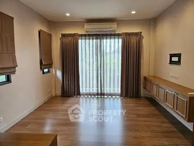 Spacious living room with wooden flooring and large windows for natural light.
