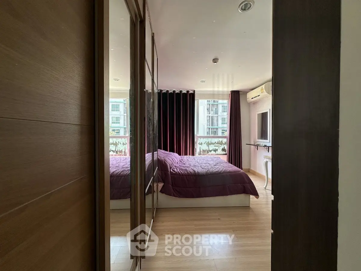Spacious bedroom with modern decor and large window offering natural light.