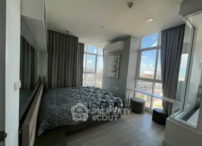Modern bedroom with large windows offering stunning city views and stylish decor.