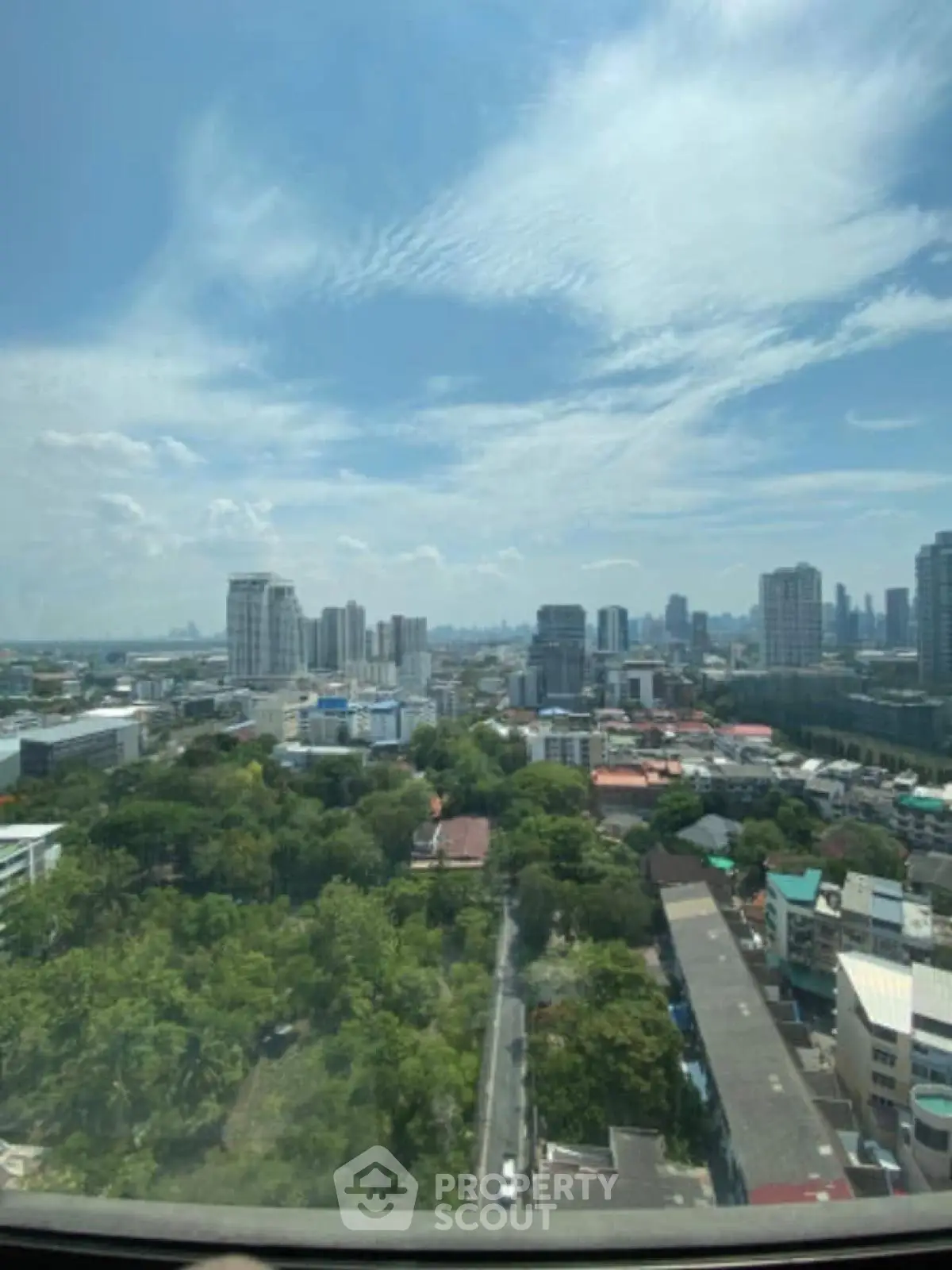 Stunning cityscape view from high-rise window showcasing urban skyline and lush greenery.