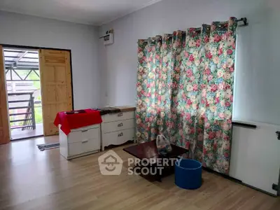 Charming living room with floral curtains and wooden flooring, perfect for cozy gatherings.