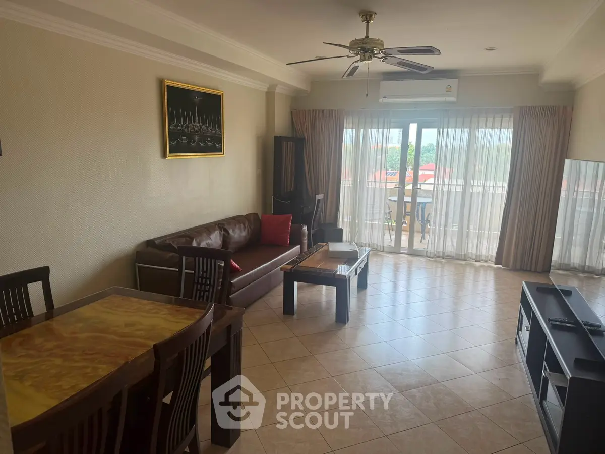 Spacious living room with elegant decor and large windows offering natural light and balcony access.