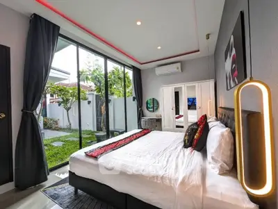 Luxurious bedroom with garden view, modern decor, and large glass doors in a stylish home.