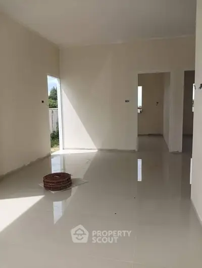 Spacious unfurnished room with glossy tiled floors and natural light.