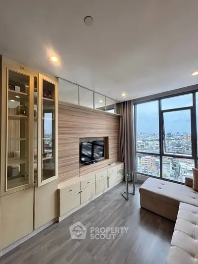 Modern living room with city view, featuring sleek built-in storage and large windows for natural light.