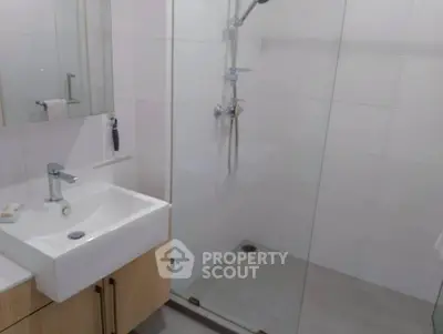 Modern bathroom with sleek glass shower and stylish sink in contemporary apartment.