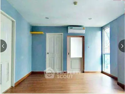 Spacious empty room with wooden flooring and large windows