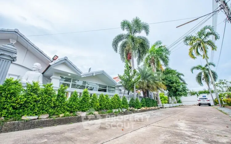 Stunning tropical home with lush greenery and palm trees lining the driveway.