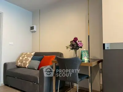 Cozy living room with modern sofa and dining table, perfect for small spaces.