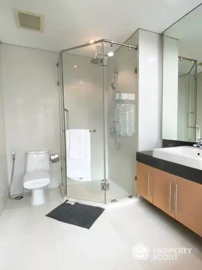 Sleek modern bathroom with glass shower enclosure, large mirror, and stylish vanity in a bright, clean space, perfect for contemporary living.