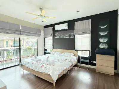 Spacious bedroom with modern decor and large windows offering natural light and a balcony view.