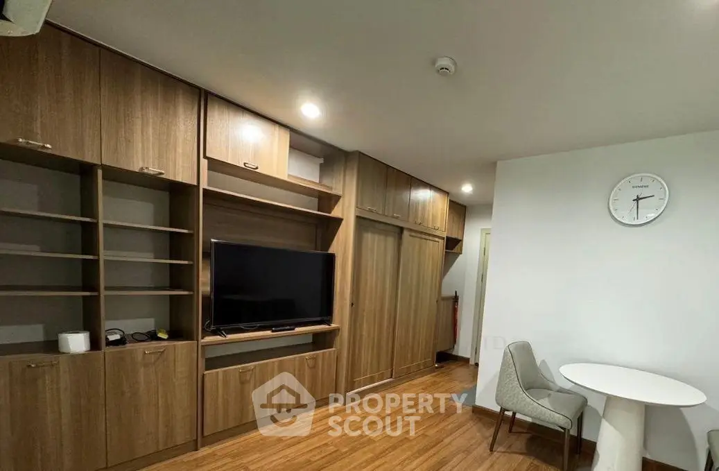Modern living room with wooden flooring, built-in shelves, and a cozy dining area.