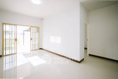 Spacious empty room with large sliding glass doors and bright natural light.