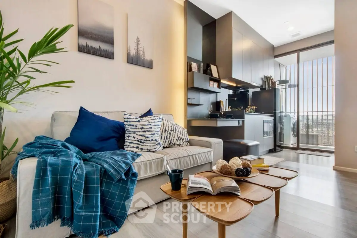 Modern living room with open kitchen and balcony view, featuring stylish decor and cozy seating area.
