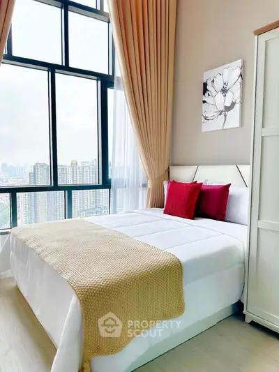 Modern bedroom with large windows offering stunning city views, featuring elegant decor and cozy bedding.