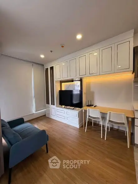 Modern living room with sleek furniture and built-in storage, featuring a cozy sofa and flat-screen TV.