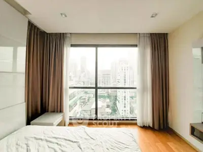 Modern bedroom with city view and large window, featuring elegant curtains and wooden flooring.