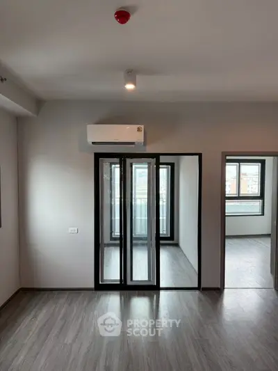 Modern apartment with sleek flooring and air conditioning, featuring a bright balcony view.