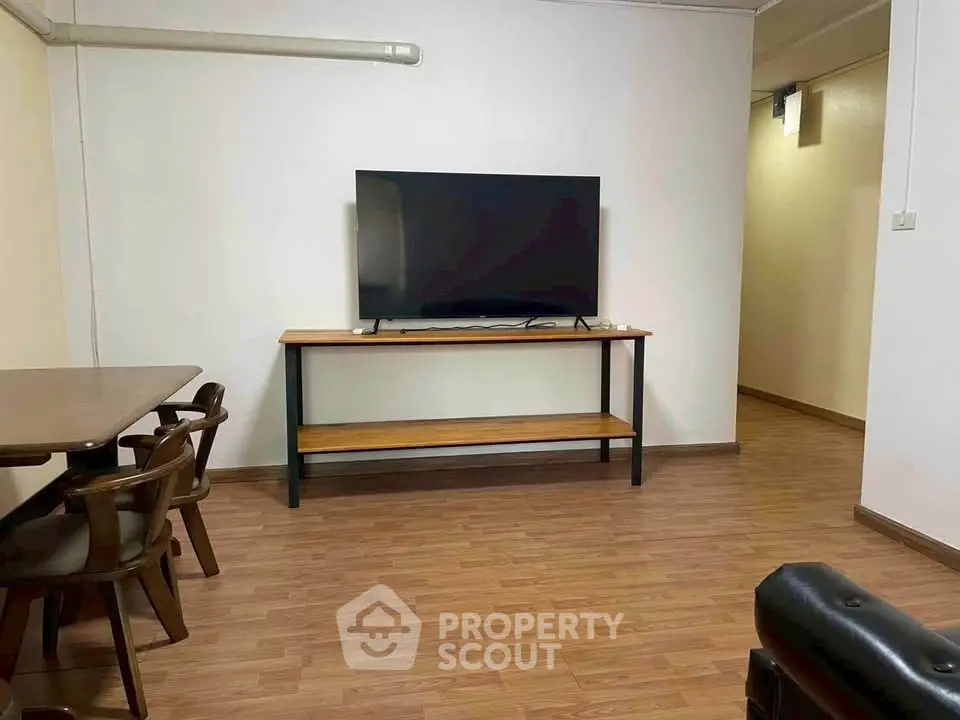 Spacious living room with modern TV setup and wooden flooring