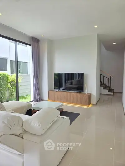 Modern living room with sleek design, large windows, and elegant staircase in a contemporary home.