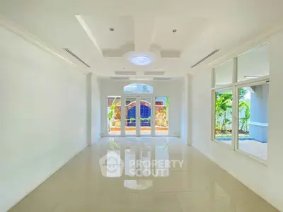 Spacious and bright living room with elegant ceiling design and large windows overlooking garden.