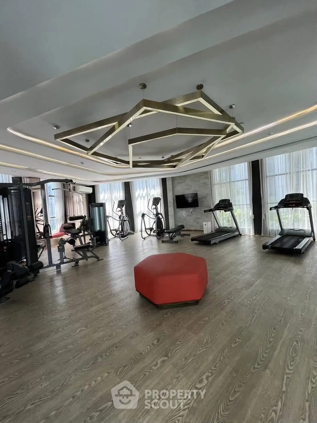 Luxurious gym with modern equipment and stylish lighting in upscale residential building.