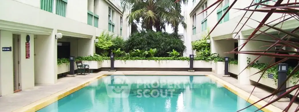 Luxurious residential pool area with lush greenery and modern architecture.