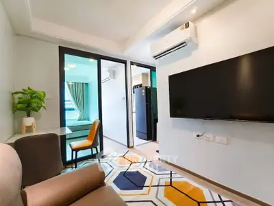 Modern living room with stylish decor and open view to bedroom, featuring air conditioning and flat-screen TV.