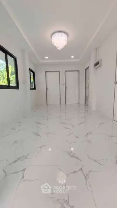 Spacious modern interior with marble flooring and elegant chandelier lighting.