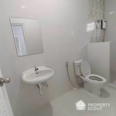 Modern bathroom with sleek fixtures and neutral tiles, featuring a toilet and sink.