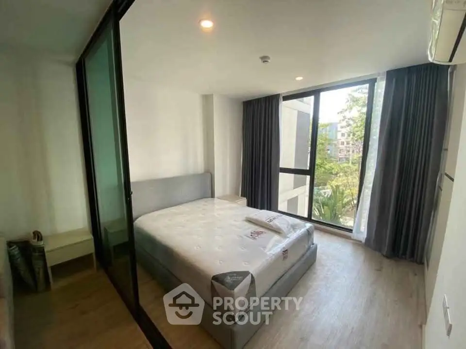 Modern bedroom with large window and minimalist design in a bright apartment.