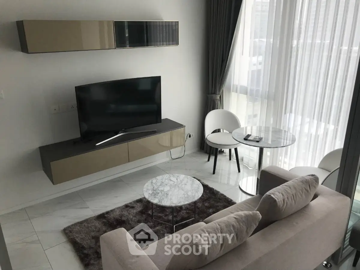 Modern living room with sleek furniture and large window offering natural light