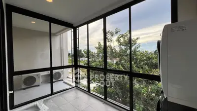 Spacious balcony with large windows and outdoor view, ideal for relaxation.