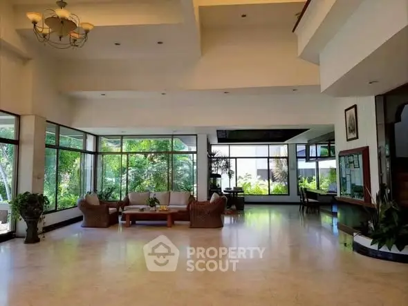 Spacious living room with large windows and garden view, featuring elegant furniture.