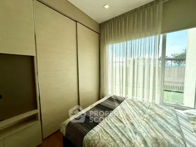 Bright bedroom with large window and built-in wardrobe, offering a serene and airy atmosphere.
