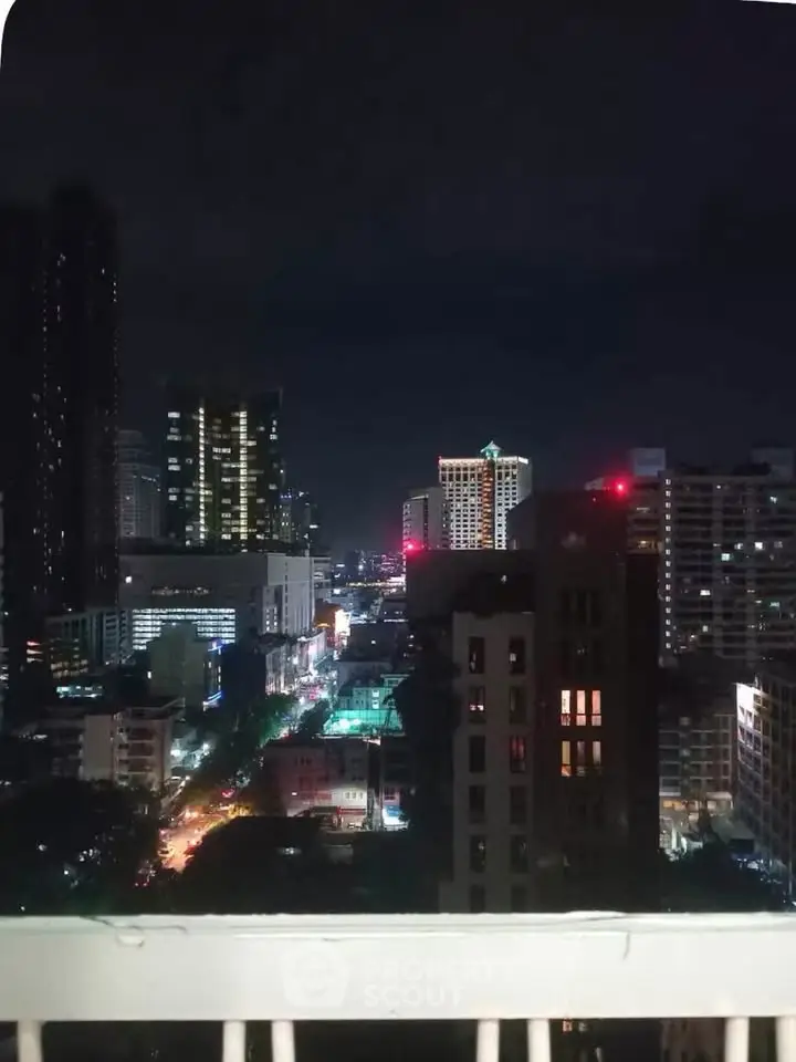 Stunning cityscape night view from a high-rise balcony, showcasing vibrant urban lights and skyline.
