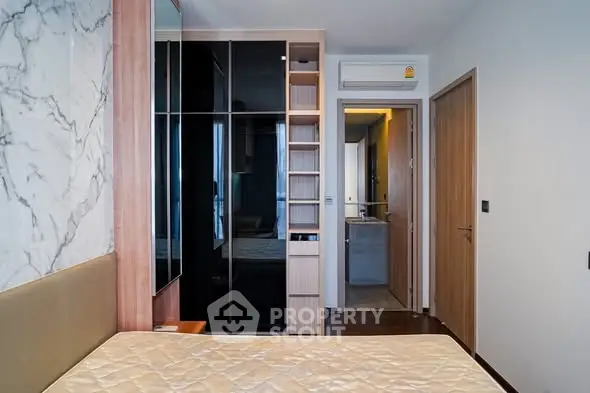 Modern bedroom with stylish wardrobe and marble accent wall in a contemporary apartment.