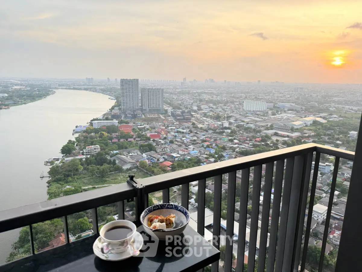 Stunning high-rise balcony view overlooking cityscape and river at sunset, perfect for relaxation.
