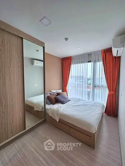 Modern bedroom with large window, wooden flooring, and mirrored wardrobe in a cozy apartment.